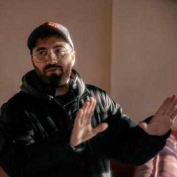 A man uses his hands to frame a shot on set.